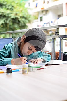 Smart Indian little boy perform thumb painting with different colourful water colour kit during the summer vacations, Cute Indian