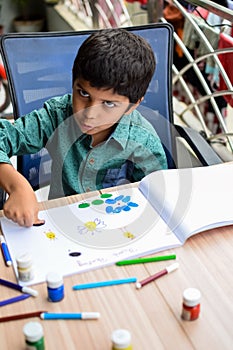 Smart Indian little boy perform thumb painting with different colourful water colour kit during the summer vacations, Cute Indian