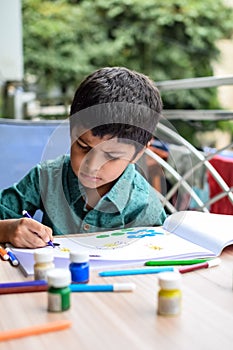 Smart Indian little boy perform thumb painting with different colourful water colour kit during the summer vacations, Cute Indian