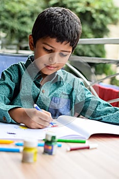 Smart Indian little boy perform thumb painting with different colourful water colour kit during the summer vacations, Cute Indian