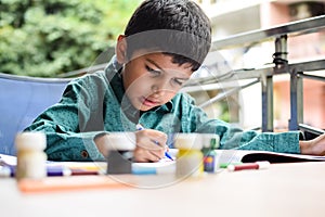 Smart Indian little boy perform thumb painting with different colourful water colour kit during the summer vacations, Cute Indian