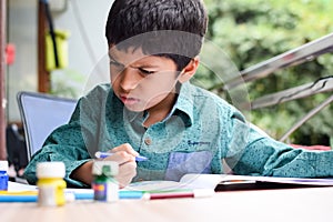 Smart Indian little boy perform thumb painting with different colourful water colour kit during the summer vacations, Cute Indian