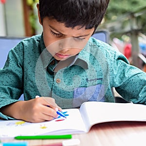 Smart Indian little boy perform thumb painting with different colourful water colour kit during the summer vacations, Cute Indian