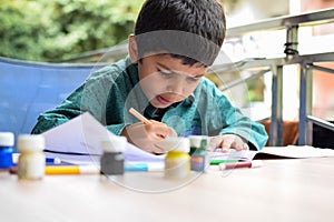 Smart Indian little boy perform thumb painting with different colourful water colour kit during the summer vacations, Cute Indian