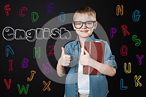 Smart kid putting his thumb up and feeling happy to learn English