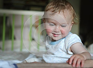 Smart kid sits on a bed in a bright room.