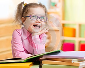 Smart kid in spectacles reading books in her room photo