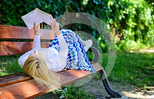 Smart lady relaxing. Girl lay bench park relaxing with book, green nature background. Woman spend leisure with book