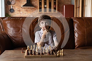 Smart little boy play chess at home thinking