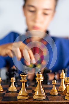 Smart little boy playing chess, a teen grandmaster with vintage chess board