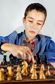 Smart little boy playing chess, a teen grandmaster with vintage chess board