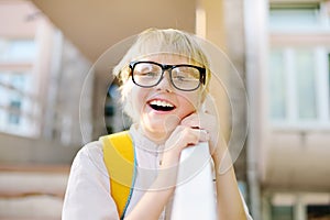 Smart little child with backpack on the stairs of school building. Quality education for children. Portrait of funny nerd