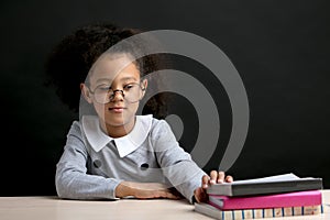 Smart little girl with glasses choosing a book to read