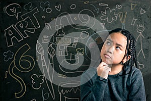 Smart little girl smiling in front of a blackboard