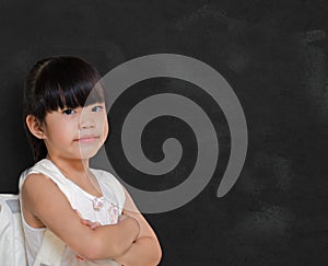 Smart little girl smiling in front of a blackboard.