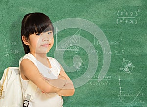 Smart little girl successful standing in front of a blackboard.