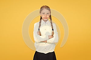 Smart little girl on yellow background. education concept. back to school. unhappy girl in school uniform. knowledge day