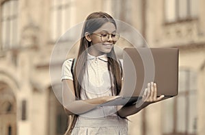 smart looking kid in gasses typing on computer searching information in internet for online school education, childhood