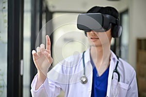 A smart male doctor in a uniform wearing virtual reality goggles in the hospital corridor