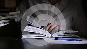 Smart man studying late at night, he is sitting at desk and reading book