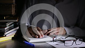 Smart man studying late at night, he is sitting at desk and reading book