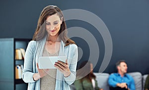 Smart management in the smart age. a young businesswoman using a digital tablet with her team in the background.