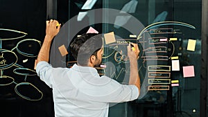 Smart manager writing business plan at glass wall on sticky notes. Tracery