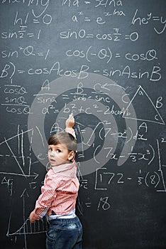 Smart, math and child writing on chalkboard in school or classroom for learning, education or solution. Genius and