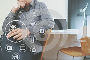 smart medical doctor holding stethoscope and thinking with laptop computer on dark wooden desk in modern office with virtual icon