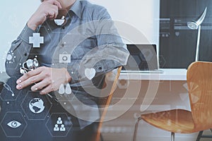 smart medical doctor holding stethoscope and thinking with laptop computer on dark wooden desk in modern office with virtual icon