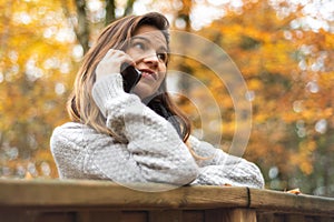 Smart phone Autumn woman talking on mobile phone in fall. Autumn girl having smartphone conversation in sun flare