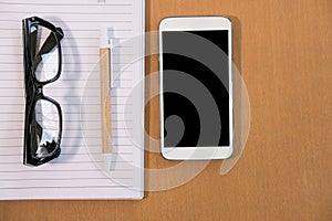 smart phone, ballpoint pen, empty notebook, eyeglasses on office
