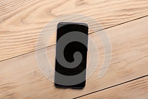 Smart phone with black screen on wooden background with copy space