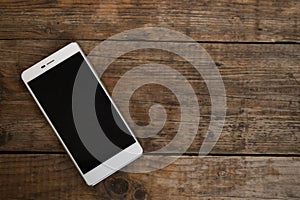 Smart phone with blank screen lying on wooden table.