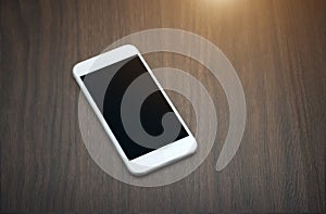 Smart phone with blank screen lying on wooden table