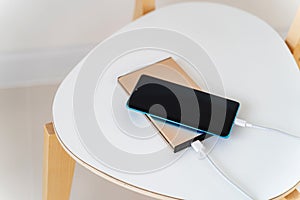 Smart phone charging with charger power bank on white chair