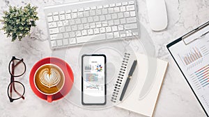 Smart phone with charts and reports on office desk workplace.