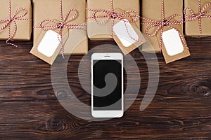 Smart phone with christmas presents on wooden background top view. Online holiday shopping concept. Flat lay, text space. Internet