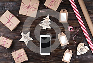 Smart phone with christmas presents on wooden background top view. Online holiday shopping concept. Flat lay, text space. Internet