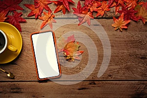 Smart phone, coffee cup and autumn maple leaves on wooden table.