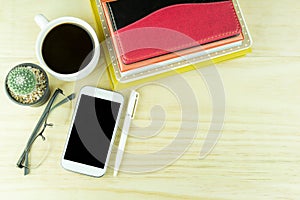 Smart phone,coffee cup,glasses, cactus and note book on wooden t