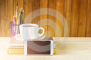 Smart phone,coffee cup,and stack of book on wooden table background.