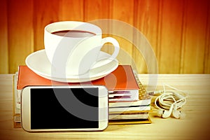 Smart phone,coffee cup,and stack of book on wooden table