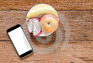 Smart phone with fruit (banana,appke,dragon fruit) on wooden flo