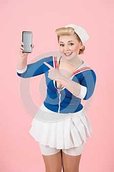 Smart-phone in hand of exited pin-up blonde girl. Smiled and happy woman propose to look in smart-phone