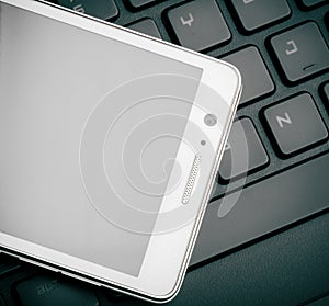 Smart Phone On Keyboard Close Up