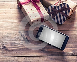 Smart phone near gift boxes. Clipping path included.