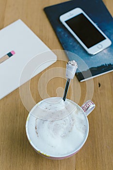 Smart phone with notebook and cup of strong coffee on wooden background.