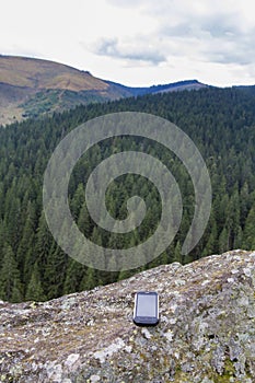 Smartphone on a rock in a mountain landscape.