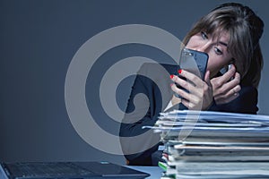 Smart phones as most distractions of productivity in work. Young beautiful female worker looking in telephone and doing makeup